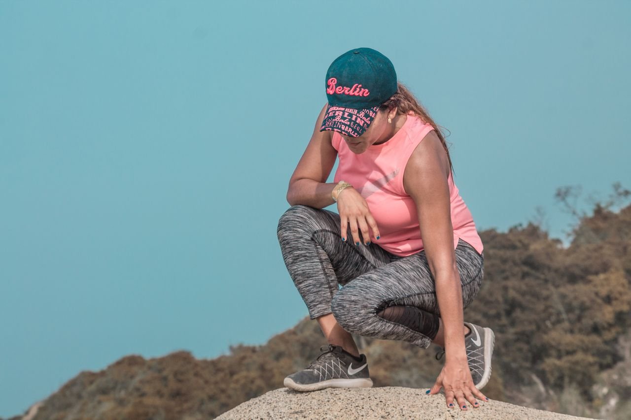 Woman in sporty attire resting on a rock in Santa Marta, Colombia outdoors.