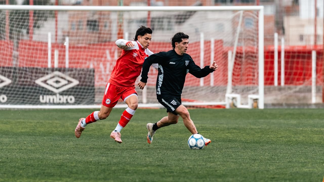 Two soccer players in action during a competitive match on a green field.
